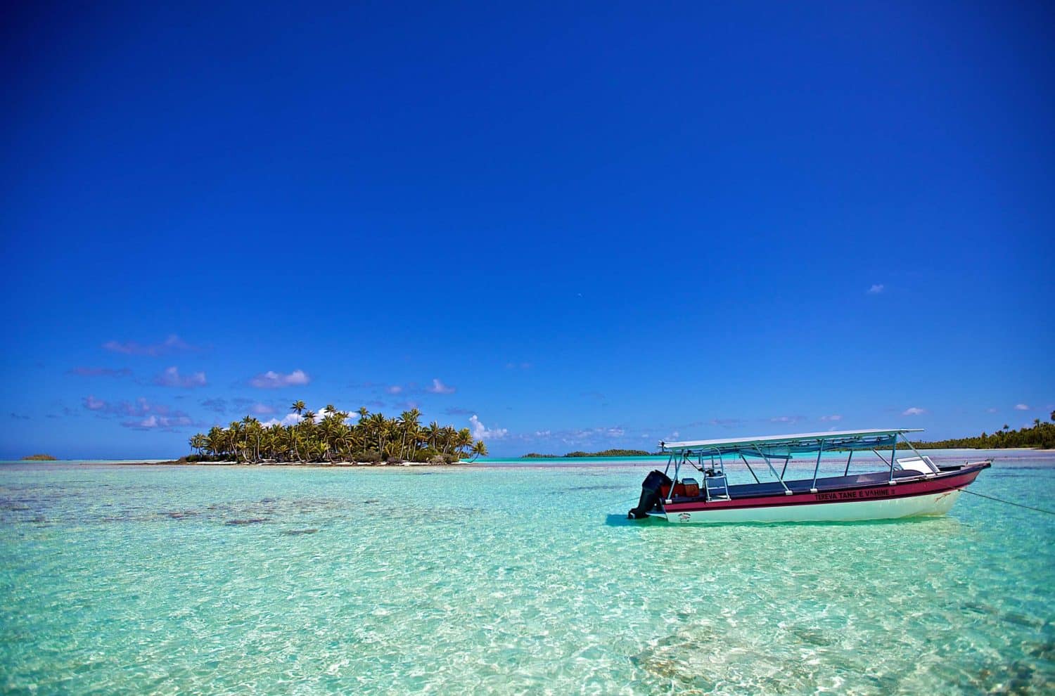 Tuamotuøyene. En øde øy i turkist vann og en liten båt