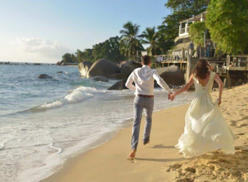 Brudepar som løper på en vakker strand