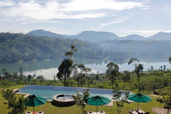 Et hotels hage med basseng, solsenger og flott utsikt mot en innsjø og fjell i det fjerne
