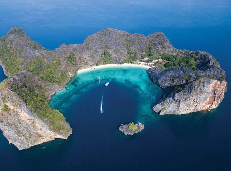 Nydelig halvsirkelformet øy med fjell og nydelig sandstrand og blå lagune