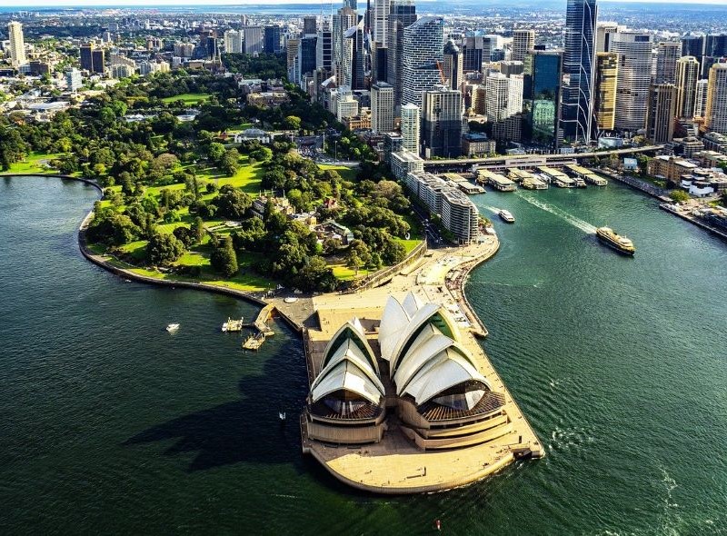 Operahuset i Sydney med parken og skyskrapere i bakgrunnen.